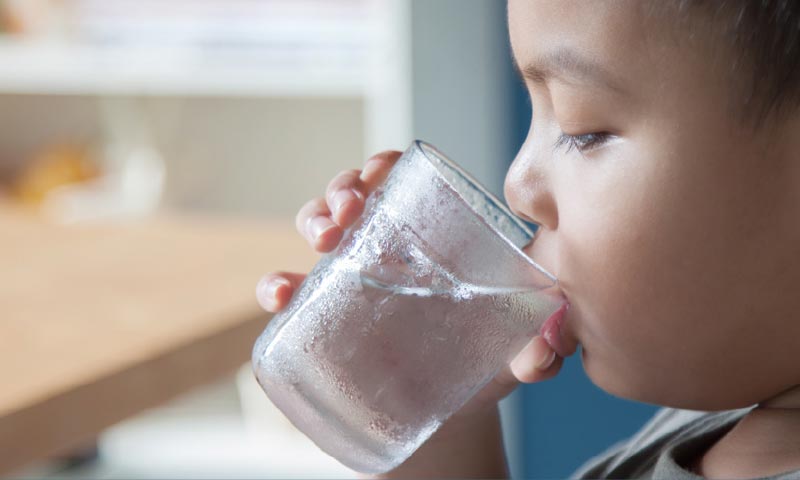 child drinking water from glass