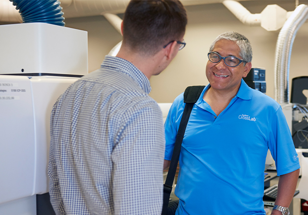CrossLab tech in blue shirt talking to a man in the lab