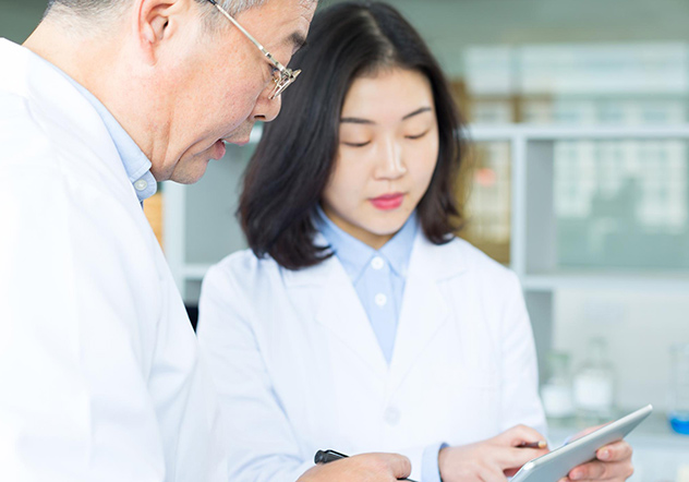 Two scientists in lab discussing over a tablet