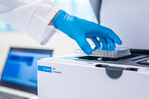 Lab technician putting a sample plate into the Agilent 4200 TapeStationDx system.