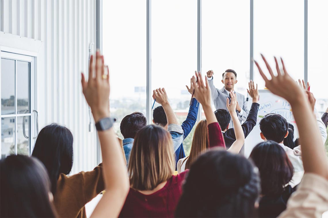 Classroom full of people with hands raised