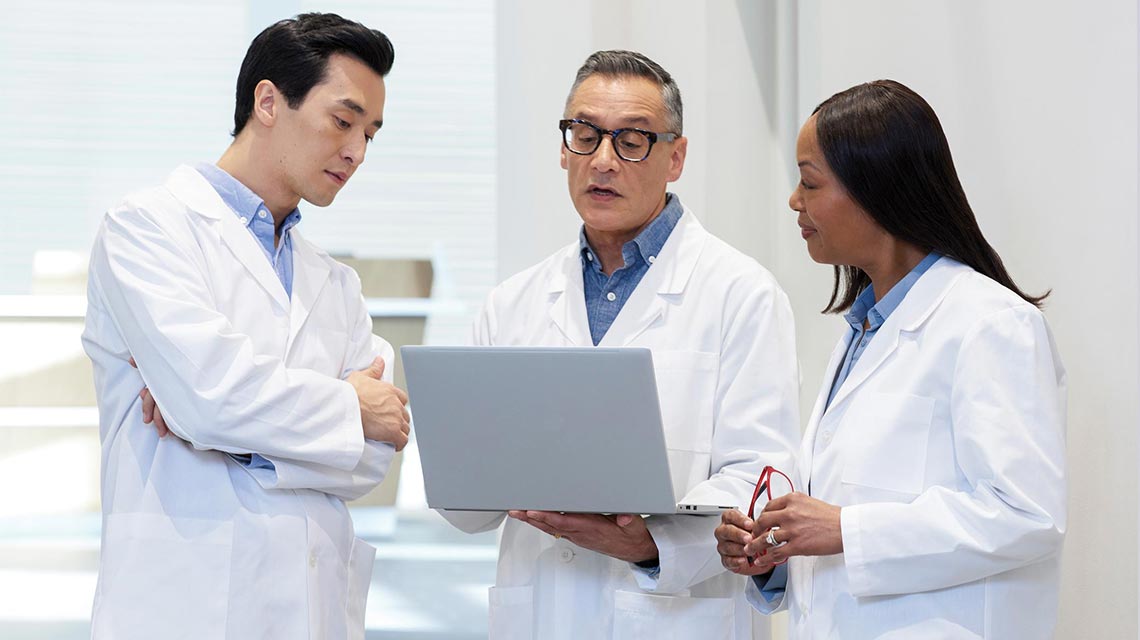 Three lab technicians viewing resources on a laptop
