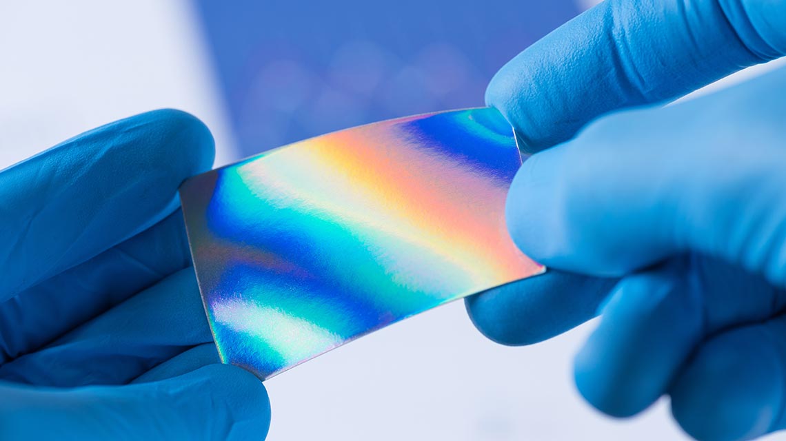 Thin, iridescent material in scientist's hands