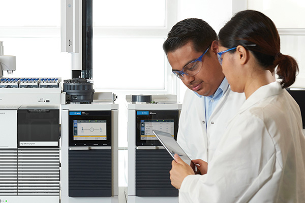 Two scientists looking at tablet in front of Intuvo 9000 GC