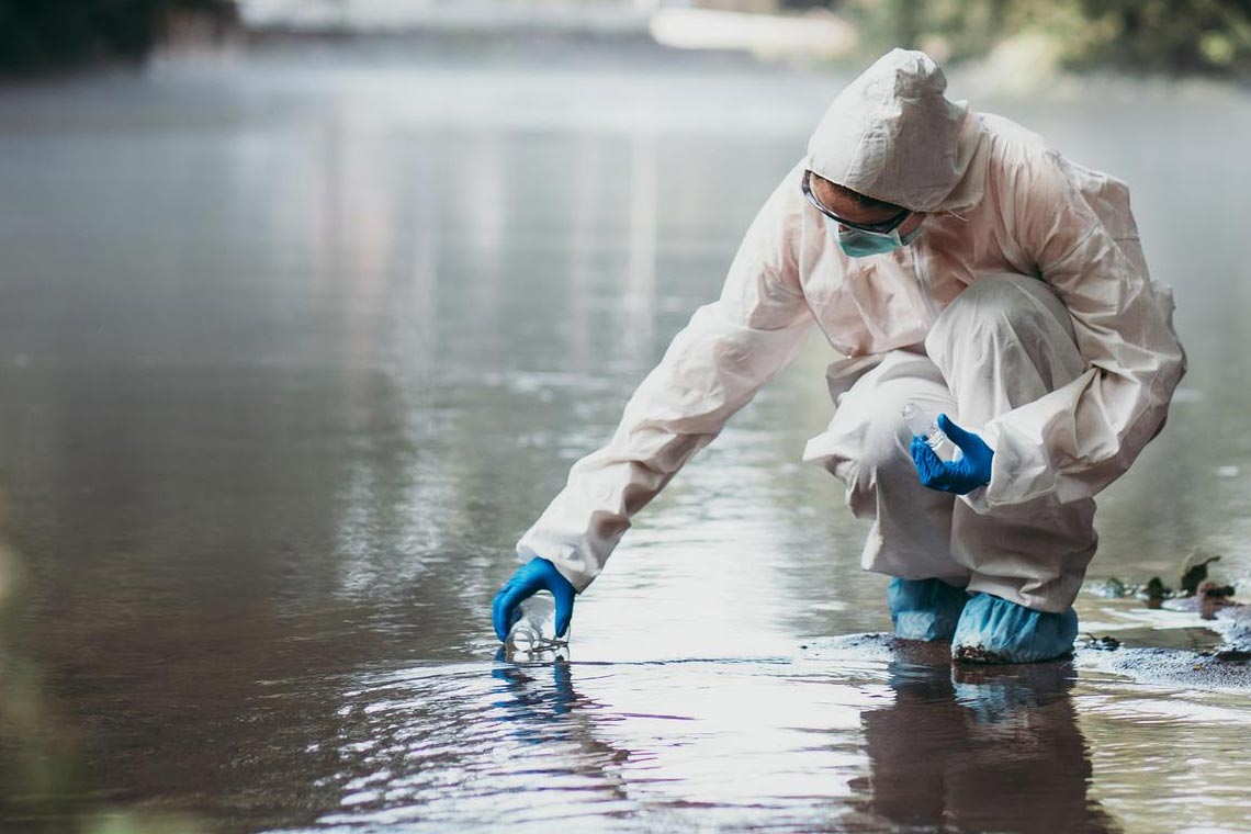 Scientist collecting water samples from a stream